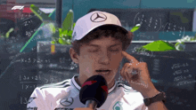 a man wearing a mercedes hat is talking into a microphone with mathematical equations behind him