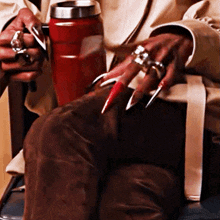 a woman with long red nails is holding a red cup