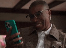 a woman wearing glasses and a plaid jacket looks at her phone