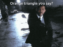 a man in a suit and tie is walking down a street with the words orange triangle you say