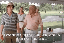 a group of men are standing next to each other on a golf course and one of them is talking about cheeseburger .