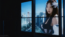 a woman is looking out of a window at a city skyline .