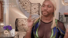 a man with blonde hair and a beard is wearing a blue and green dress and waving .