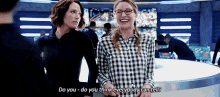 two women are standing next to each other and laughing . one of the women is wearing glasses .