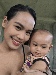 a woman holds a baby in her arms and the baby is wearing a shirt with an elephant on it