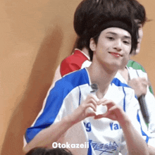 a boy in a ya shirt makes a heart shape with his hand