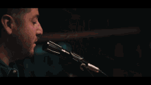 a man is singing into a microphone while playing an acoustic guitar