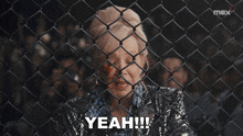 a woman is behind a chain link fence and says yeah