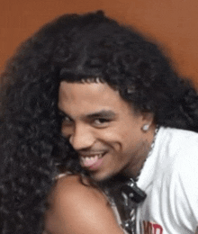 a man with long curly hair is wearing a white shirt that says ' limited ' on it