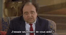 a bald man in a suit and tie is sitting in a chair and talking .