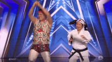 a man and a girl in karate uniforms are dancing on stage
