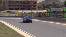 a car is driving down a race track with a building in the background that says ' xtreme ' on it