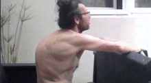 a man without a shirt is sitting on a chair with his arms outstretched .