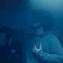 a man in a blue hoodie is making a funny face