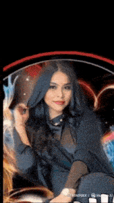 a woman in a black dress is sitting in front of a black background