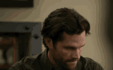 a man with long hair and a beard looks down at something