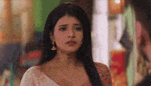 a woman is looking at a man in a room and making a sad face .