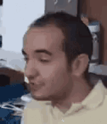a close up of a man 's face with his eyes closed and a yellow shirt on .