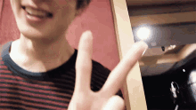 a man is making a peace sign with his fingers .