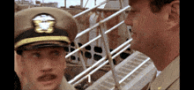a man in a military uniform stands next to another man wearing a hat that says u.s. navy