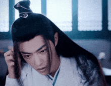 a man with long black hair is wearing a white shirt and a black hat