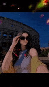a woman wearing sunglasses takes a selfie in front of the coliseum
