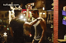 a couple of men are hugging each other in front of a brick wall .