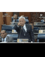 a man in a suit and tie is giving a speech in front of a parliament and the word pak is on the screen