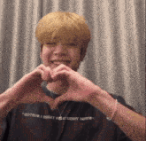 a man making a heart shape with his hands wearing a shirt that says where there i went