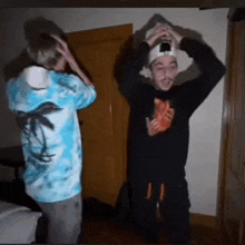 two men are standing next to each other in a room and one is wearing a tie dye shirt with palm trees on it