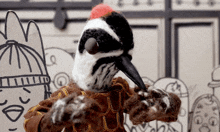 a stuffed bird with a red beak is standing in front of a cardboard drawing of a man