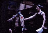 a man wearing a mask holds another man 's arm