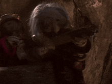 a couple of dolls are standing next to each other and one is holding a sword