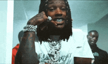 a man with dreadlocks is wearing a necklace and a ring