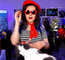 a woman wearing sunglasses and a red hat is holding a donut