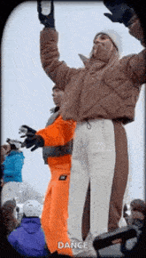 a group of people are standing in the snow with their arms in the air and a woman is holding a bottle of beer .