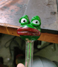 a person is holding a pipe with a green frog on it