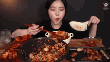 a woman with chopsticks is eating a bowl of food