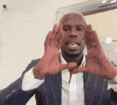 a man in a suit and white shirt is making a heart with his hands