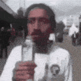 a man with a beard is holding a bottle of water in front of his face .