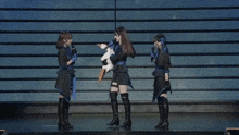 three women are standing on a stage and one has a sword in her hand