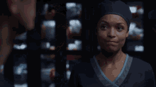 a woman wearing a scrub hat looks at a man in a dark room