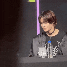 a man is sitting at a table with a bottle of water and a mirror