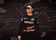 a man wearing sunglasses and a black shirt that says thieves