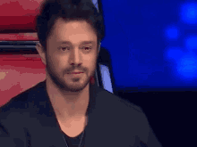 a man with a beard is sitting in a chair with his eyes closed and tears running down his face .