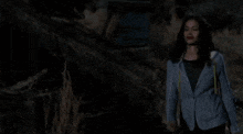 a woman is standing in the dark holding a man 's arm .