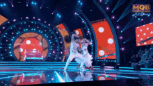 a man and a woman are dancing on a stage with mqb written on the bottom