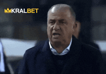 a man in a suit stands in front of a sign that says kralbet