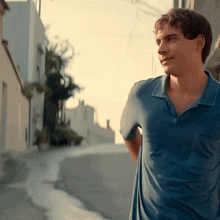 a young man in a blue shirt is standing on a sidewalk