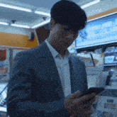 a man in a suit is looking at his phone in front of a sign that says ' a ' on it